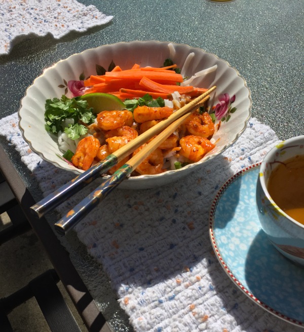 Photo of Satay Noodle Salad with Shrimp and tea being eaten on a patio.